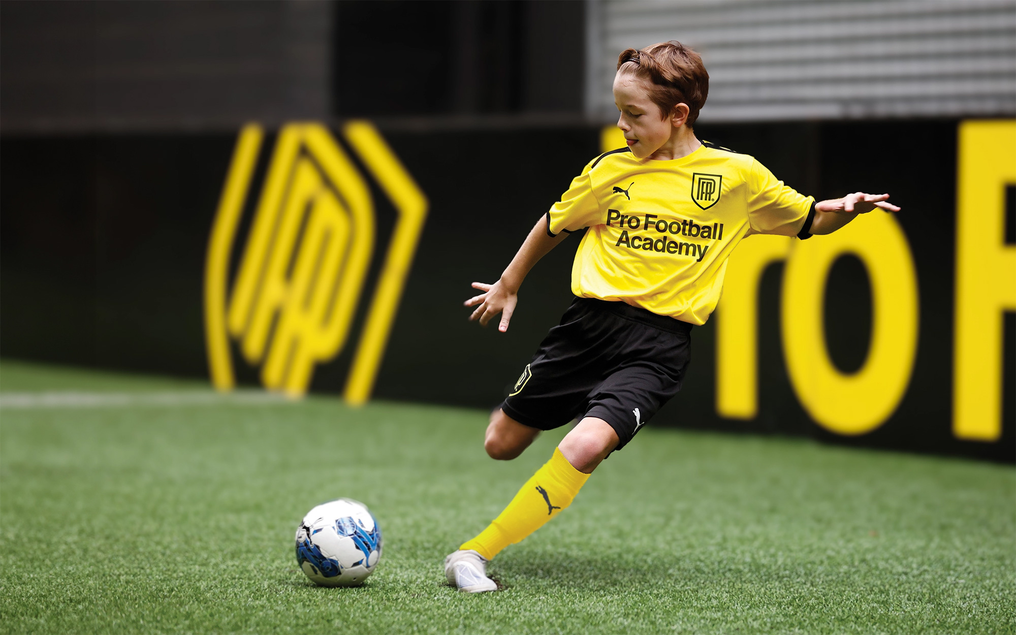 Kids football coaching with a boy kicking a ball